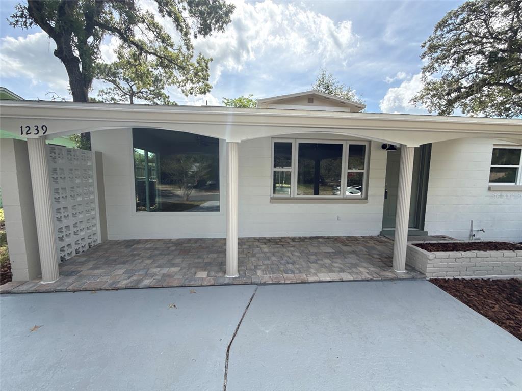 A white house exterior features a covered porch with stone pavers and two white columns — 1239 SE 18TH TERRACE, GAINESVILLE, FL