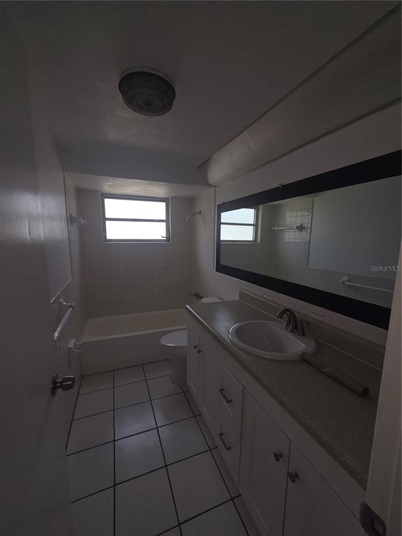 A bathroom features white tile flooring, a white vanity with a sink, and a bathtub — 1505 ROUNDTREE ROAD, HOLIDAY, FL