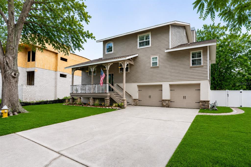 A two-story house with tan siding, a front porch, and an attached two-car garage — 14 BAYWOOD DRIVE, PALM HARBOR, FL