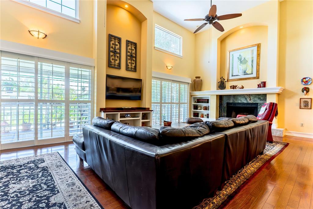 A spacious living room features a large leather sectional, a fireplace, and high ceilings — 14 BAYWOOD DRIVE, PALM HARBOR, FL
