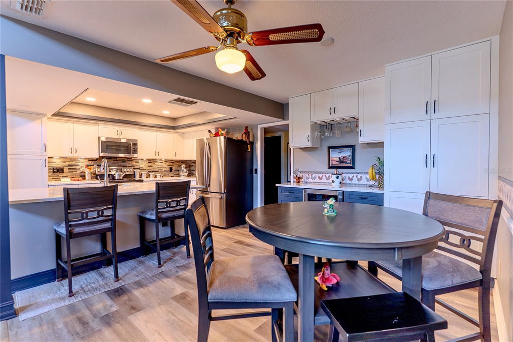 A kitchen and dining area featuring white cabinets, stainless steel appliances, and a ceiling fan — 14 BAYWOOD DRIVE, PALM HARBOR, FL
