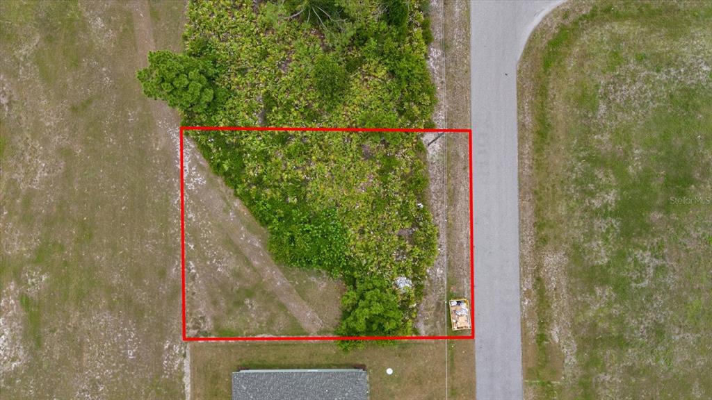 An aerial view shows a rectangular, partially wooded vacant lot bordered by a paved road — 66 LATEEN SAIL DRIVE, PLACIDA, FL