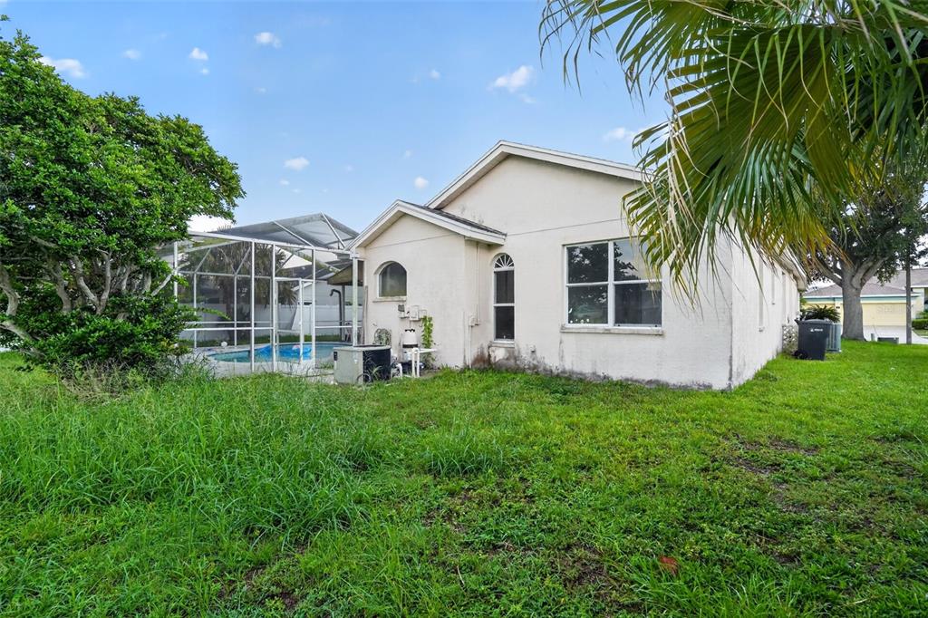 The exterior of a beige house with a screened-in pool and an overgrown grassy yard — 13126 PRESTWICK DRIVE, RIVERVIEW, FL