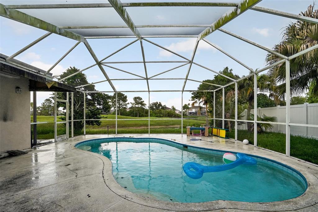 A swimming pool sits inside a screened-in lanai overlooking a grassy golf course — 13126 PRESTWICK DRIVE, RIVERVIEW, FL