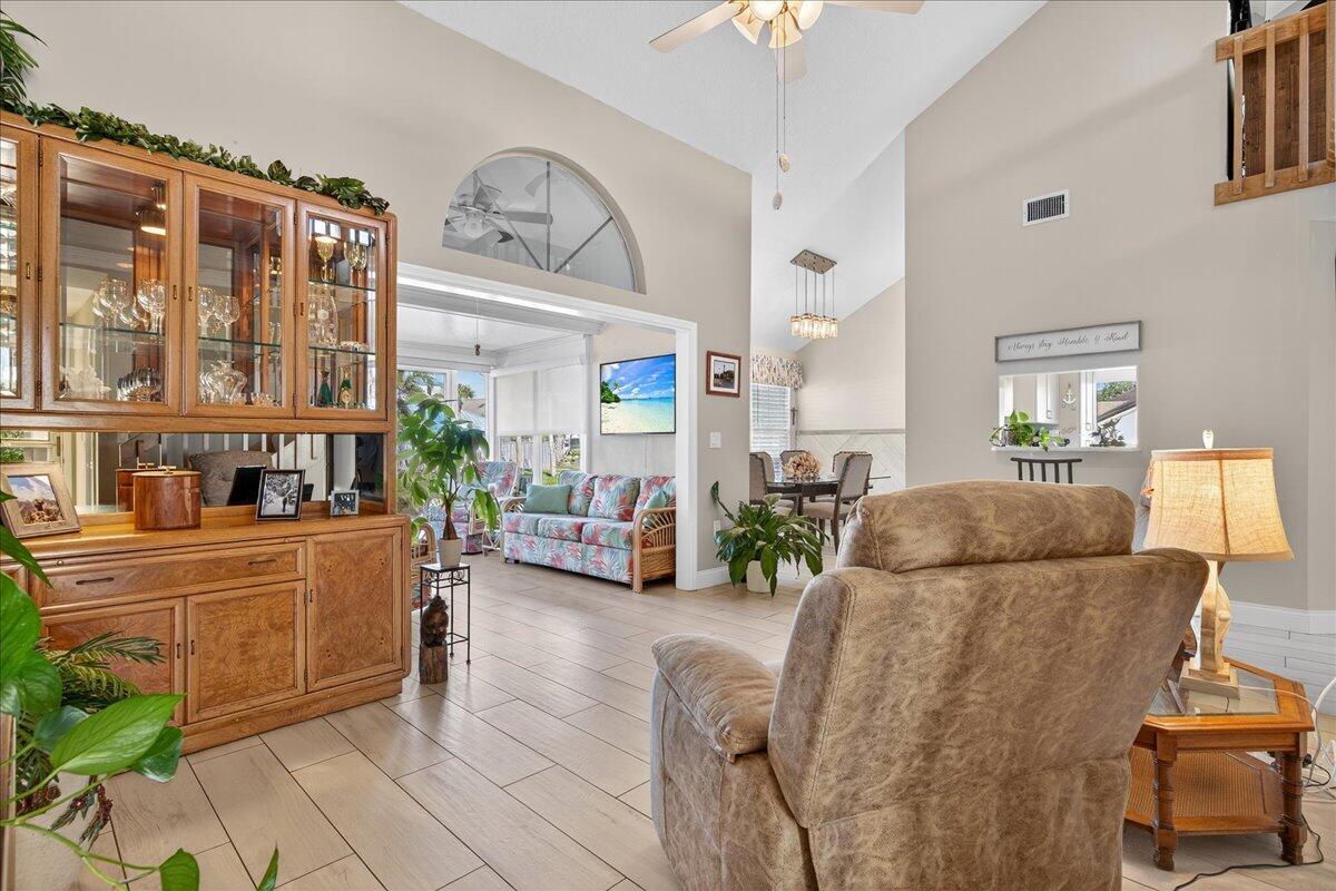 A living room features a wooden hutch, a recliner, and an open view into a sunroom — 1827 Aynsley Way # 4, Vero Beach FL 32966, VERO BEACH, FL
