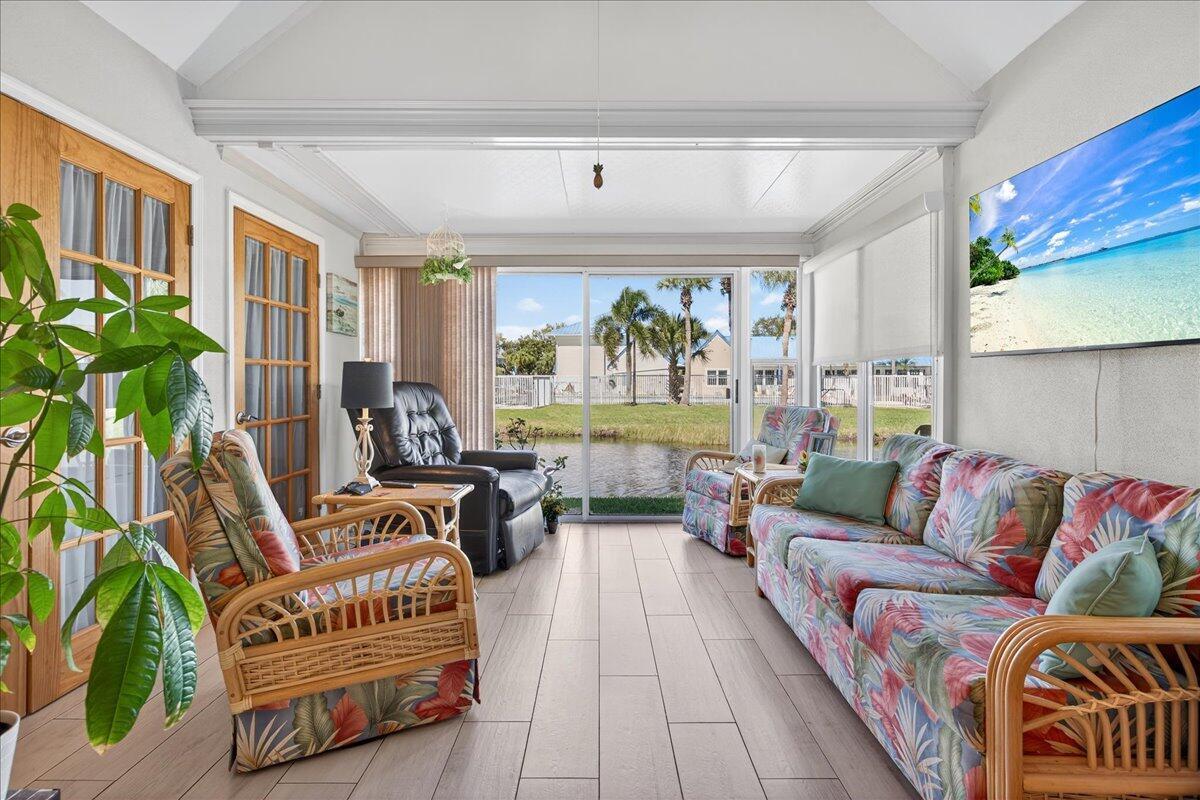A sunroom with tile flooring, wicker furniture, and a view of a pond outside — 1827 Aynsley Way # 4, Vero Beach FL 32966, VERO BEACH, FL
