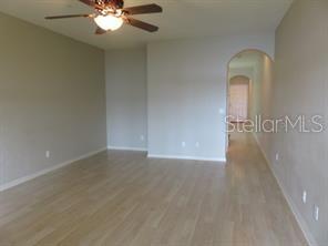 An empty room with light-colored wood flooring, a ceiling fan, and an arched doorway — 3903 45TH TERRACE W UNIT 104, BRADENTON, FL