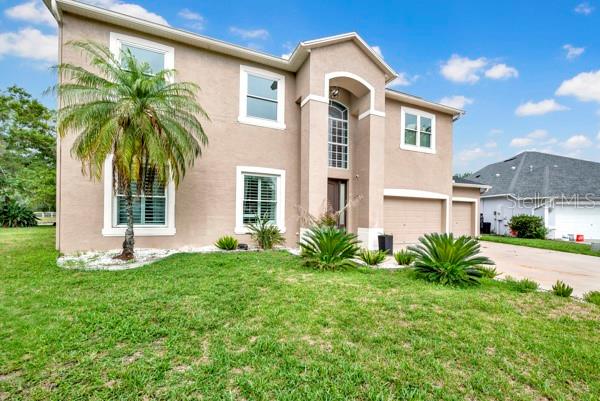 A two-story tan stucco house features a palm tree in the front yard — 3103 ASHMONTE DRIVE, LAND O LAKES, FL
