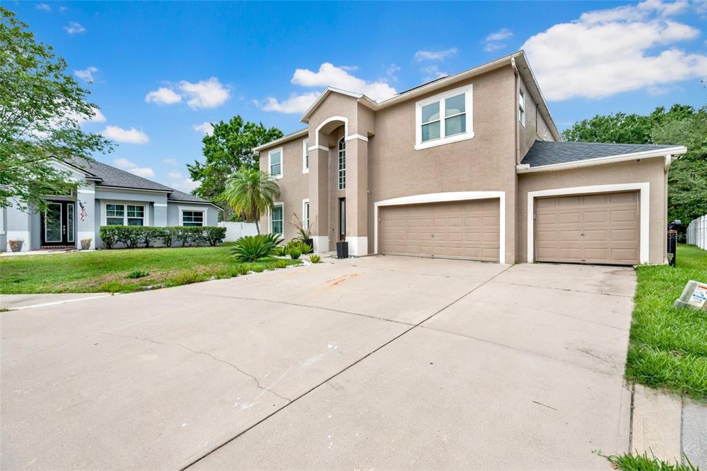 A two-story tan stucco house with a three-car garage and a concrete driveway — 3103 ASHMONTE DRIVE, LAND O LAKES, FL