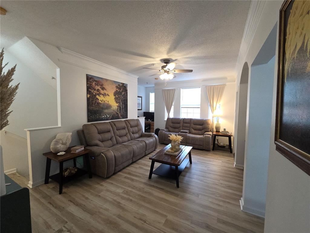 A living room features light wood-look flooring, two brown reclining sofas, and a wooden coffee table — 12110 POPPY FIELD LANE UNIT 104, ORLANDO, FL