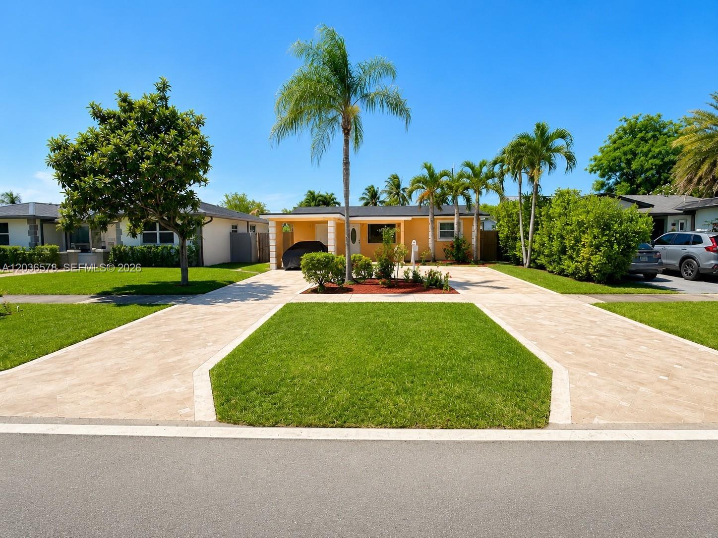 A single-story house with a paved driveway, central lawn, and palm trees under a blue sky — 3327 Taft St, Hollywood FL 33021, HOLLYWOOD, FL