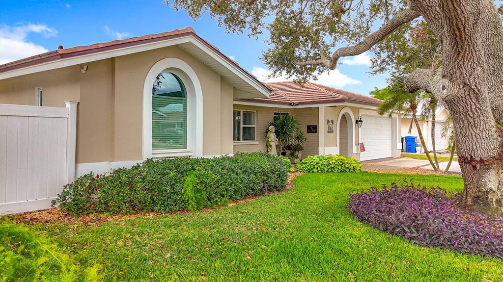 The exterior of a single-story tan house features a large arched window and a garage — 3828 48TH AVENUE S, ST PETERSBURG, FL