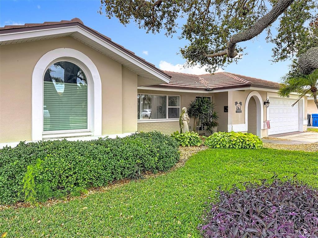 A single-story house with a beige exterior, arched windows, and a manicured front lawn — 3828 48TH AVENUE S, ST PETERSBURG, FL