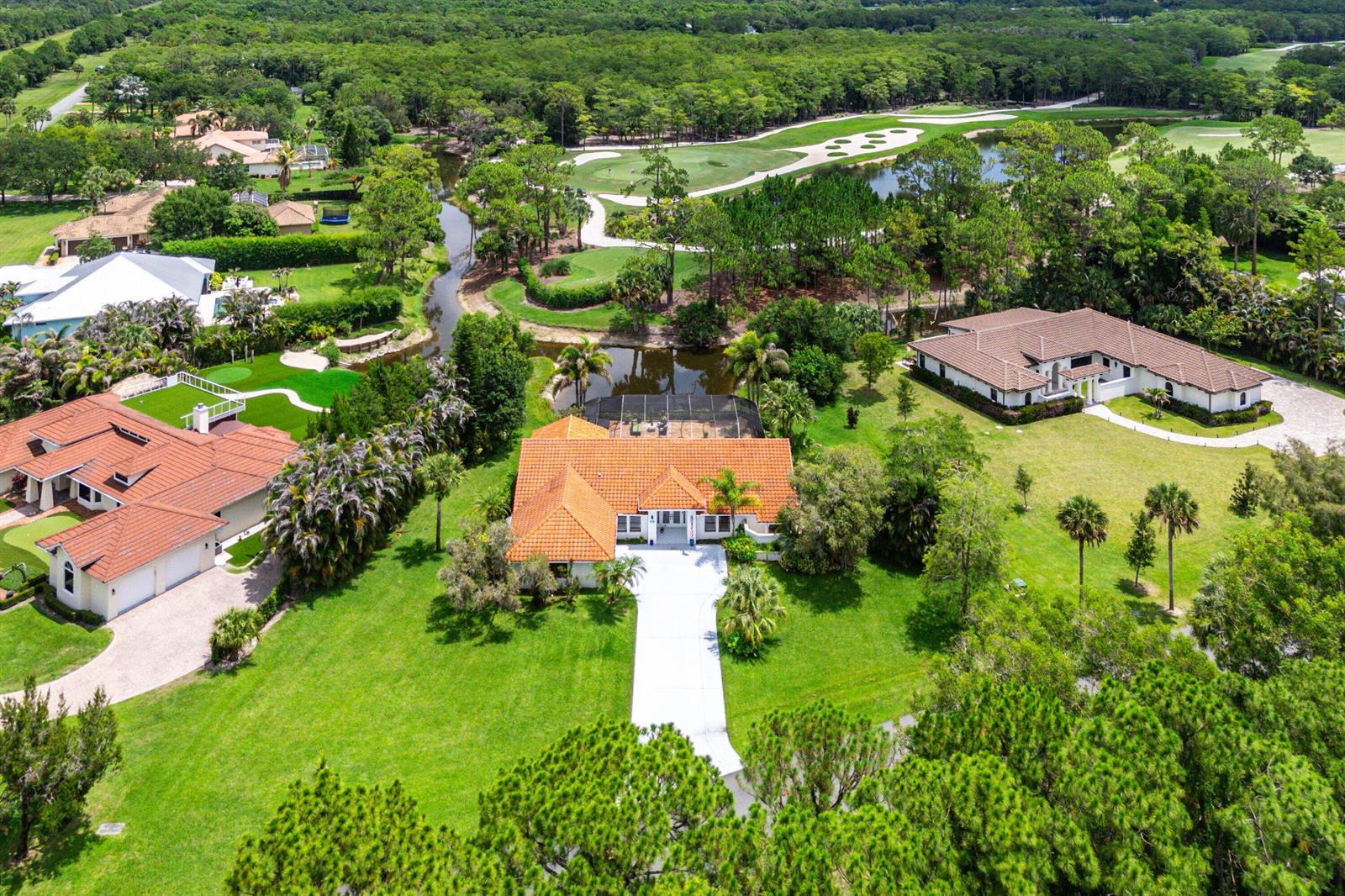 An aerial view shows a residential neighborhood with houses, green lawns, and a golf course — 1488 SE Colony Way, Jupiter FL 33478, JUPITER, FL