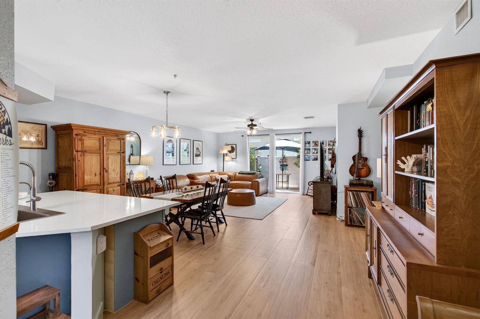 An open-concept living and dining area features wood flooring, a kitchen island, and patio access — 311 Bayfront Drive, Boynton Beach FL 33435, BOYNTON BEACH, FL