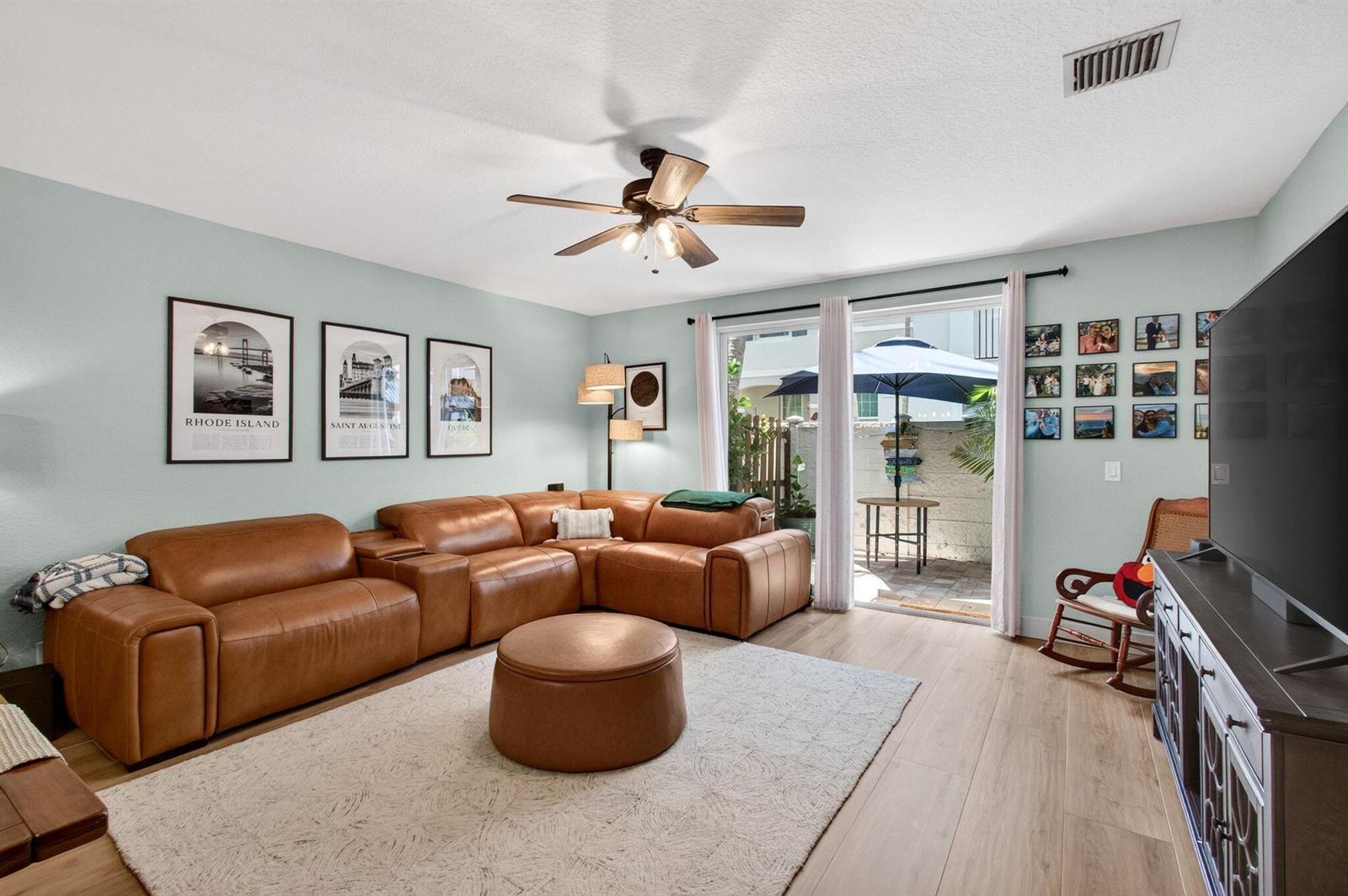 A living room features a brown leather sectional, a round ottoman, and a sliding glass door — 311 Bayfront Drive, Boynton Beach FL 33435, BOYNTON BEACH, FL
