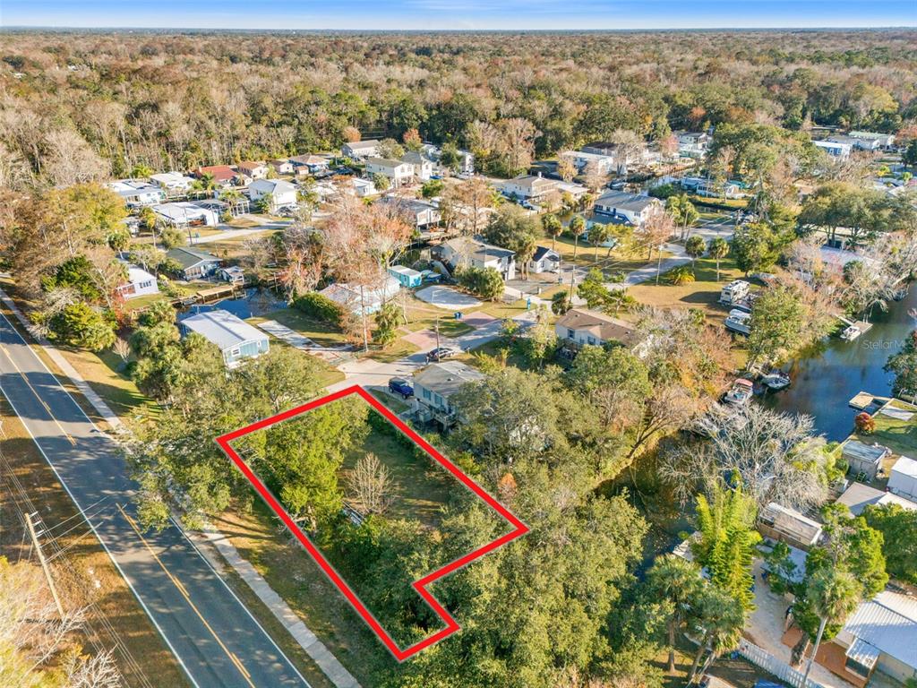 An aerial view shows a vacant, tree-covered lot outlined in red next to a road — 7287 COVENTRY COURT, WEEKI WACHEE, FL