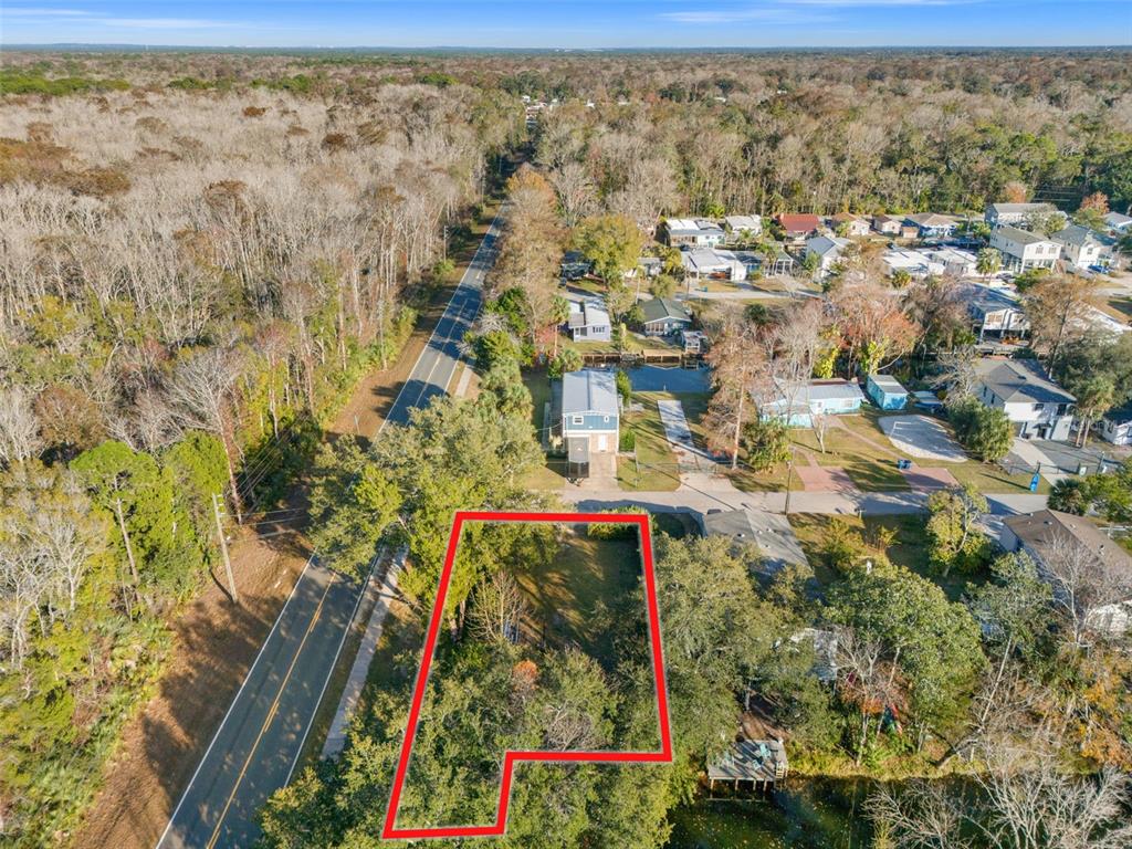 An aerial view shows a vacant, wooded lot outlined in red next to a road — 7287 COVENTRY COURT, WEEKI WACHEE, FL