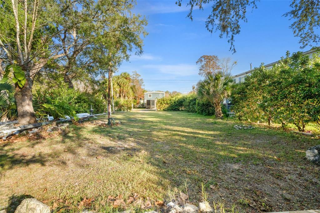 A grassy backyard features a small shed at the end of a long lot — 7287 COVENTRY COURT, WEEKI WACHEE, FL