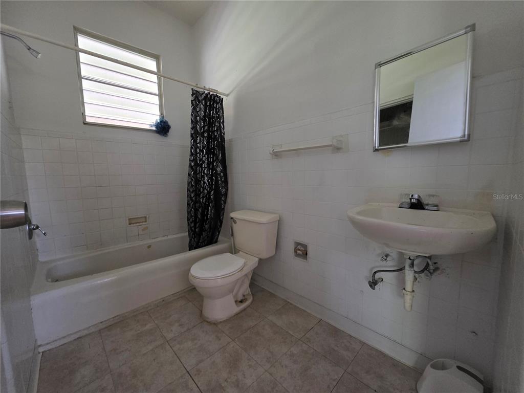 A bathroom features a white tiled tub, a toilet, and a wall-mounted sink — 150 ROMAGUERA ST, MAYAGUEZ, PR