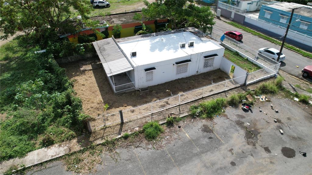 An aerial view shows a white single-story house with a metal roof and fenced yard — 150 ROMAGUERA ST, MAYAGUEZ, PR