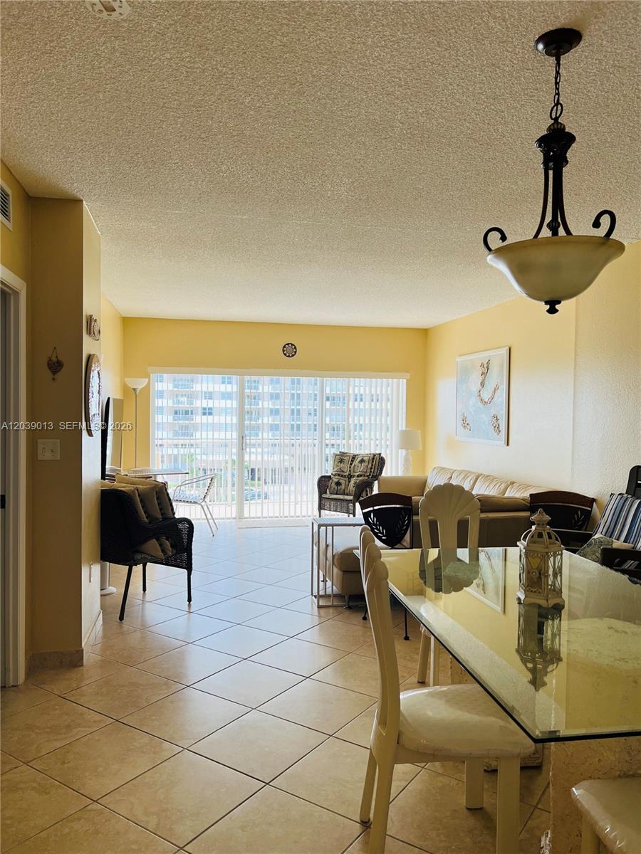 A dining and living area features tile floors, yellow walls, and a glass-topped table — 1950 S Ocean Dr # 4C, Hallandale Beach FL 33009, HALLANDALE BEACH, FL