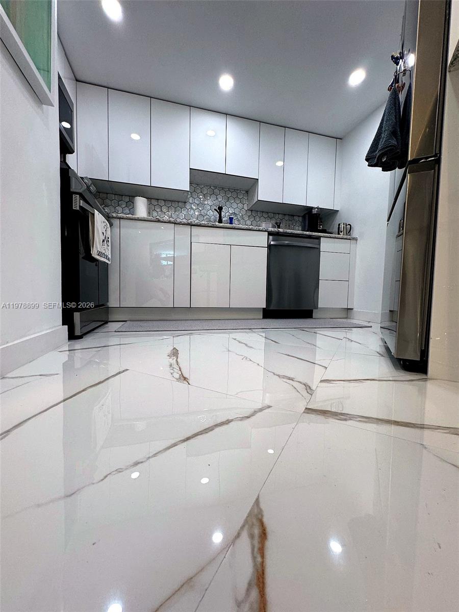 A modern kitchen features white cabinets, stainless steel appliances, and polished marble-look floor tiles — 999 Brickell Bay Dr # 710, Miami FL 33131, MIAMI, FL