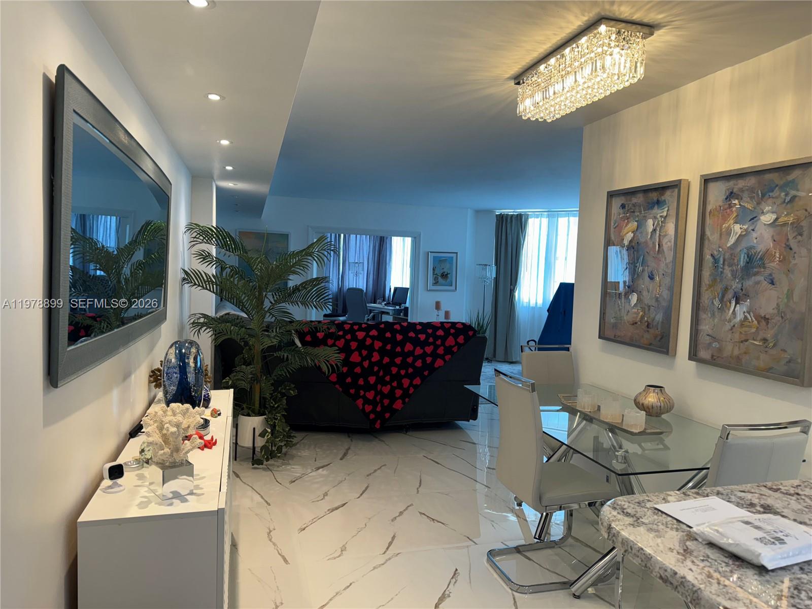 A dining area and living room feature white marble floors, modern lighting, and contemporary decor — 999 Brickell Bay Dr # 710, Miami FL 33131, MIAMI, FL