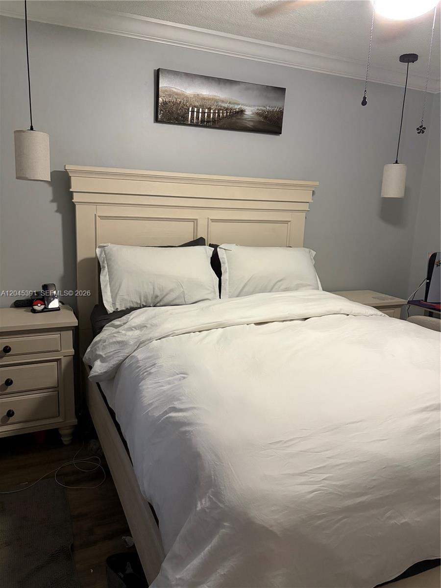 A bedroom features a white bed frame, two hanging pendant lights, and a landscape wall art — 109 Gardens Dr # 104, Pompano Beach FL 33069, POMPANO BEACH, FL