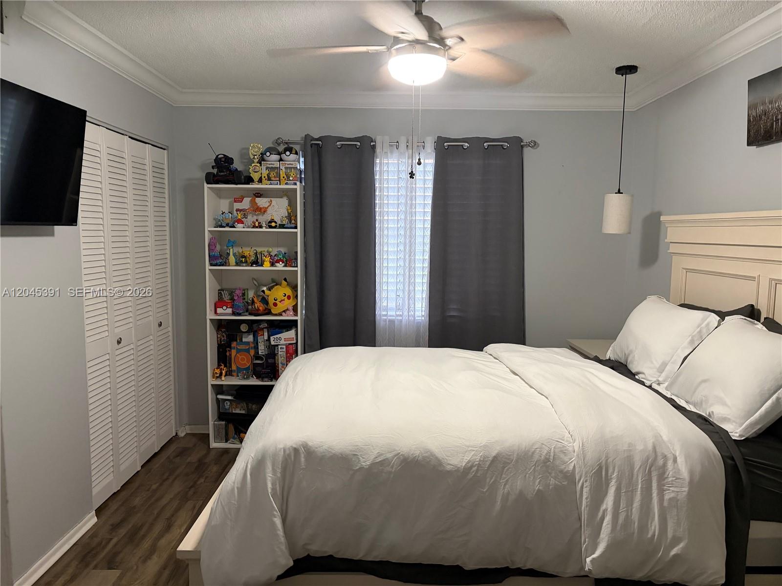 A bedroom features a bed with white bedding, a bookshelf, and a ceiling fan — 109 Gardens Dr # 104, Pompano Beach FL 33069, POMPANO BEACH, FL