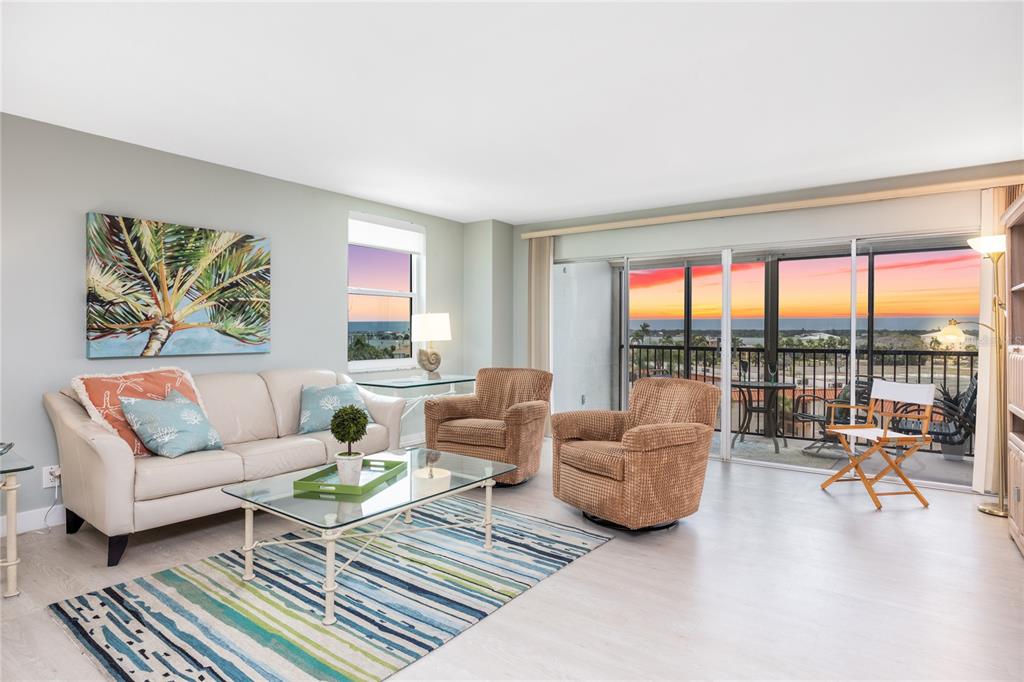 A living room features a beige sofa, two armchairs, a glass coffee table, and balcony views — 10355 PARADISE BOULEVARD UNIT 412, ST PETERSBURG, FL