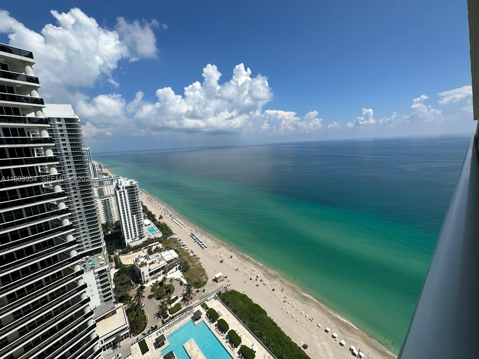 A high-angle view shows a sandy beach, turquoise ocean, and several tall residential buildings — 1830 S Ocean Dr # 4010, Hallandale Beach FL 33009, HALLANDALE BEACH, FL