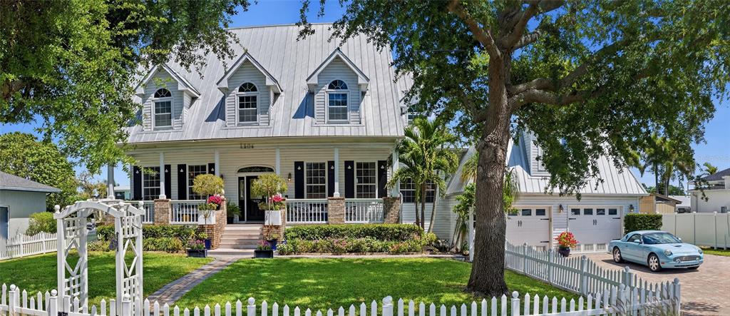 A two-story house with a metal roof, dormer windows, and a white picket fence — 4506 PINFISH LANE, PALMETTO, FL