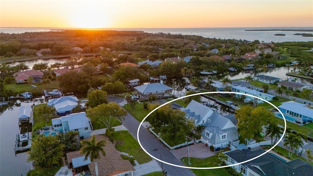 An aerial view shows a house with a metal roof surrounded by trees and water — 4506 PINFISH LANE, PALMETTO, FL
