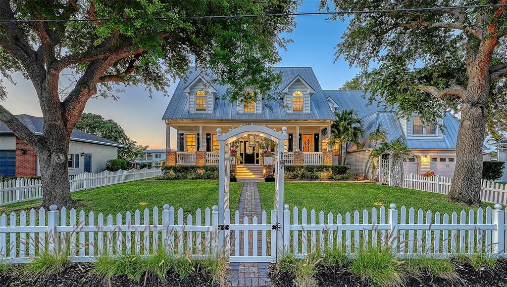 A two-story house with a metal roof, dormer windows, and a white picket fence — 4506 PINFISH LANE, PALMETTO, FL