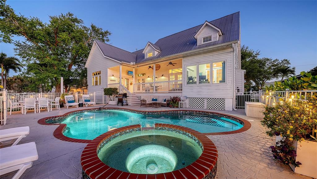 A two-story white house with a metal roof features a swimming pool and hot tub — 4506 PINFISH LANE, PALMETTO, FL