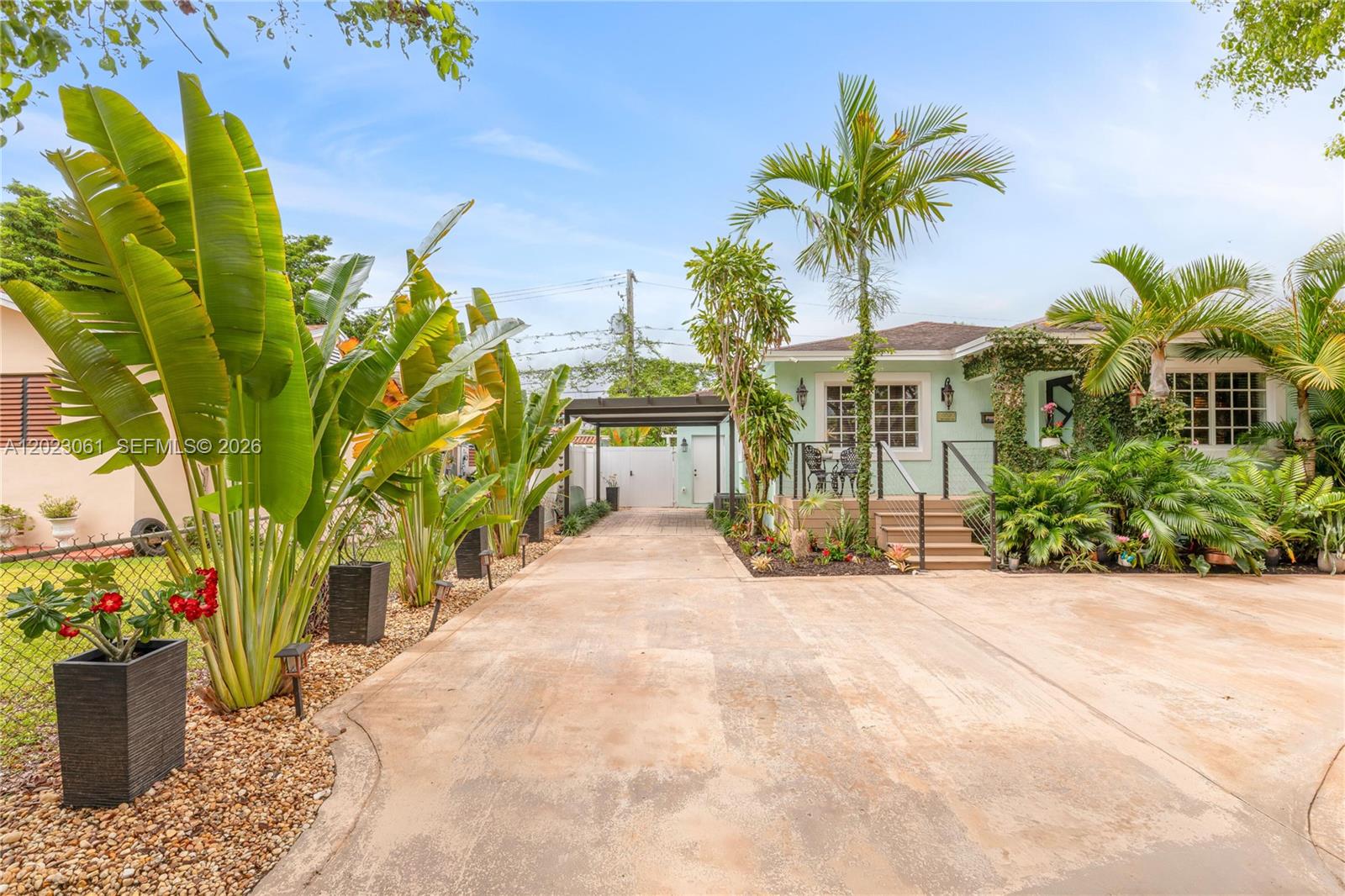 A light green house with a concrete driveway, palm trees, and a covered carport — 6520 SW 16th Ter, West Miami FL 33155, WEST MIAMI, FL
