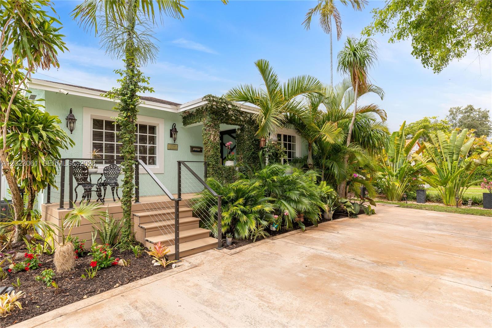 A light green house with a front porch, metal railings, and lush tropical landscaping — 6520 SW 16th Ter, West Miami FL 33155, WEST MIAMI, FL