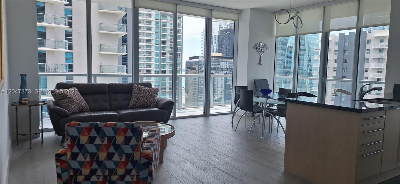 A modern apartment living and dining area features floor-to-ceiling windows with city views — 1111 SW 1 AV, Miami FL 33130, MIAMI, FL
