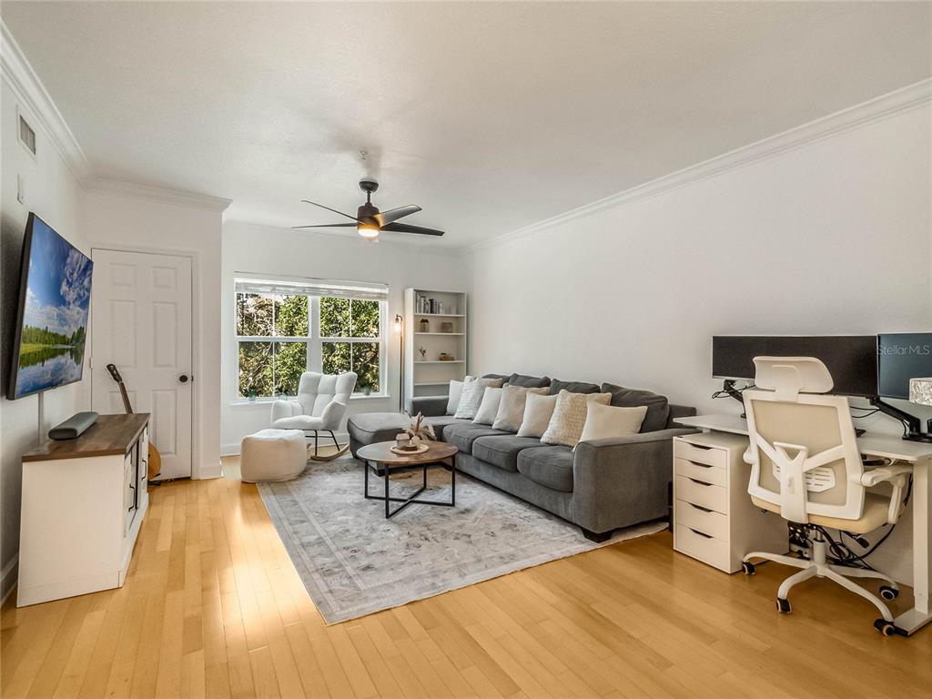 A living room features a gray sectional sofa, a desk area, and hardwood flooring — 202 E SOUTH STREET UNIT 3051, ORLANDO, FL