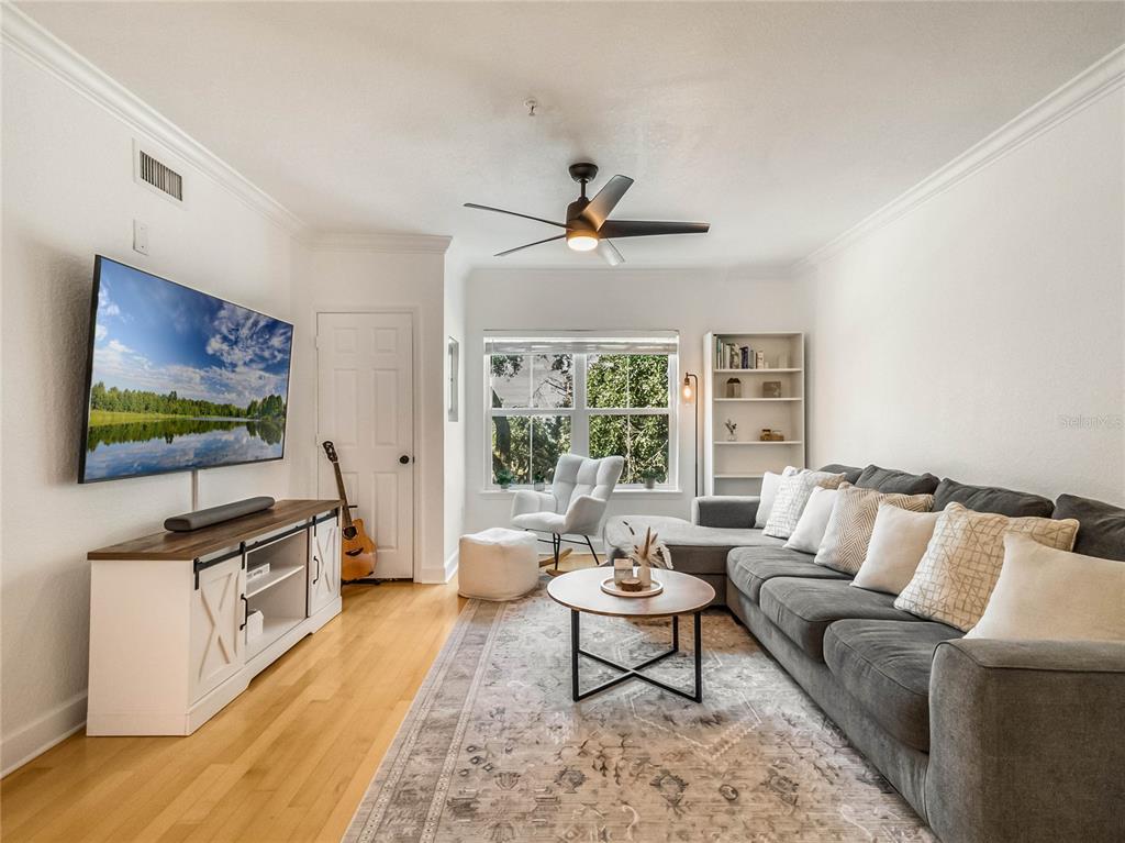 A living room features a grey sectional sofa, a television, and a wooden coffee table — 202 E SOUTH STREET UNIT 3051, ORLANDO, FL