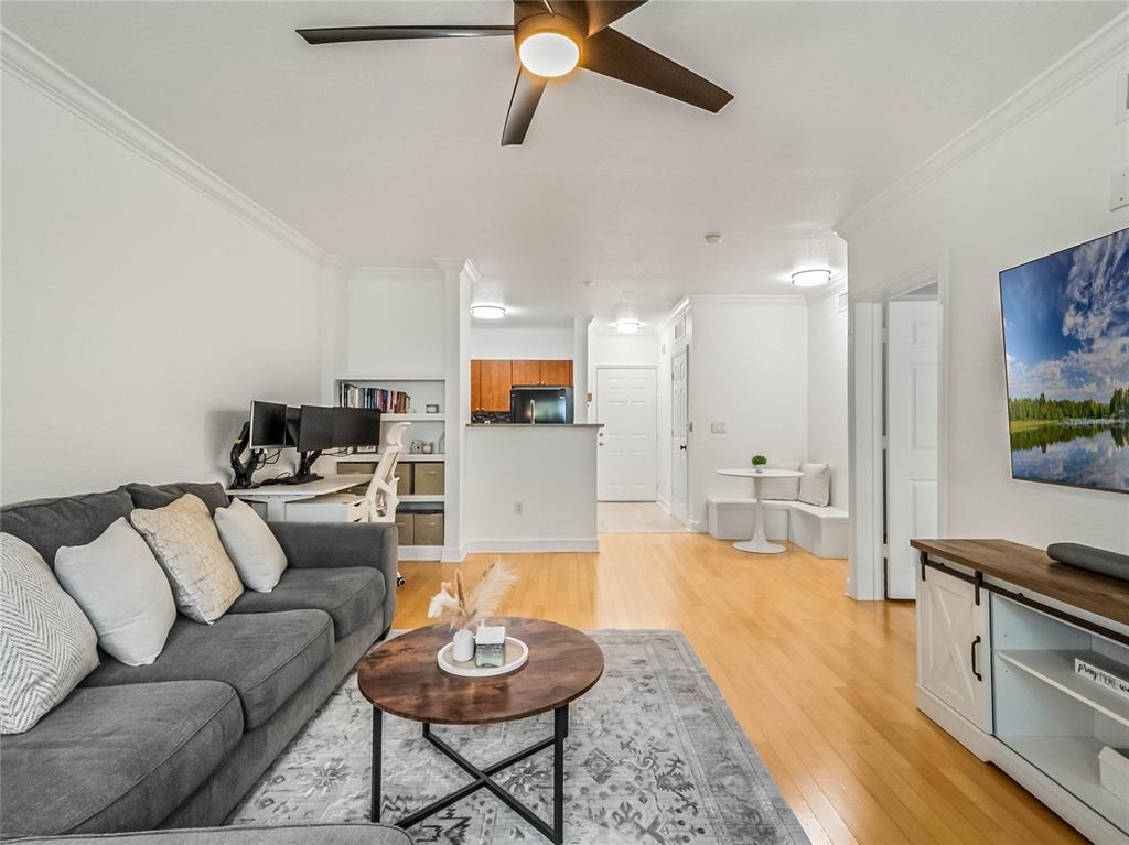 A living room features a gray sofa, a wooden coffee table, and an adjacent workspace — 202 E SOUTH STREET UNIT 3051, ORLANDO, FL