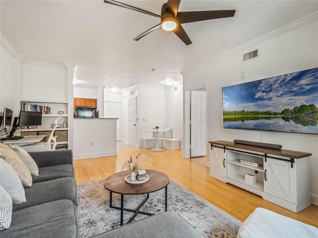 A living room features a gray sofa, a round coffee table, and a wall-mounted television — 202 E SOUTH STREET UNIT 3051, ORLANDO, FL