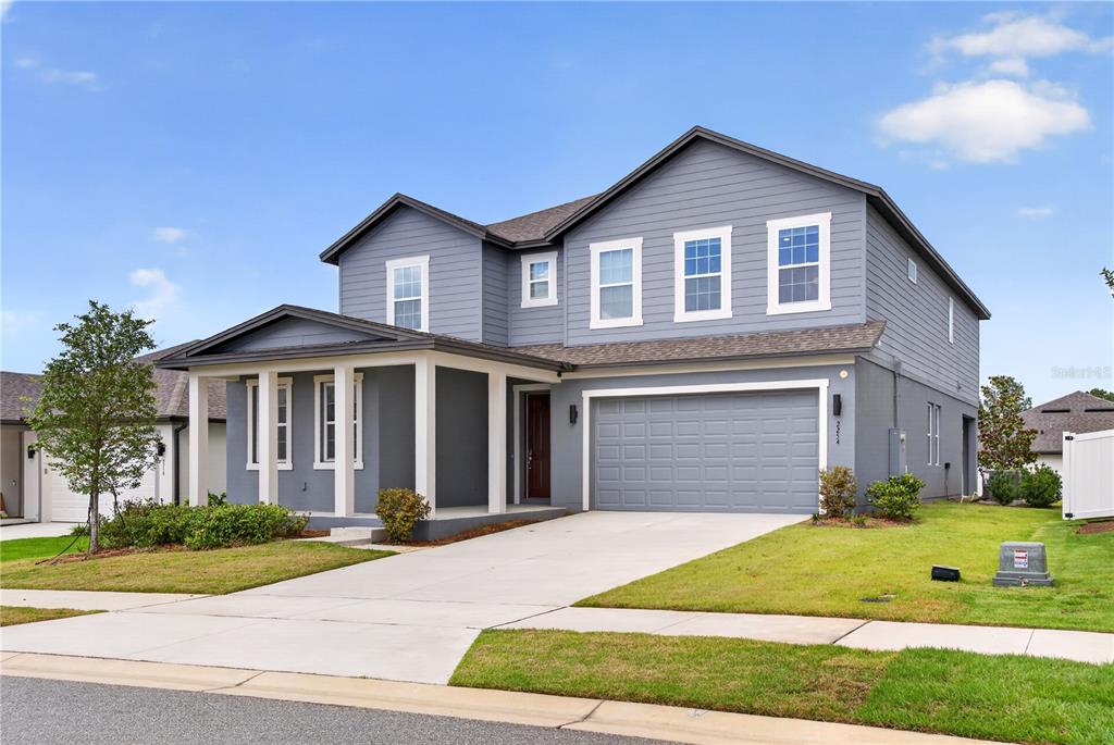 A two-story blue house with a front porch, a two-car garage, and a concrete driveway — 2254 LOST HORIZON WAY, MINNEOLA, FL