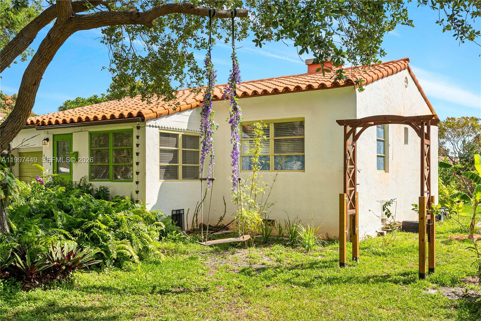 A white stucco house with a terracotta tile roof features a swing and wooden arbor — 1601 N 16th Ct, Hollywood FL 33020, HOLLYWOOD, FL