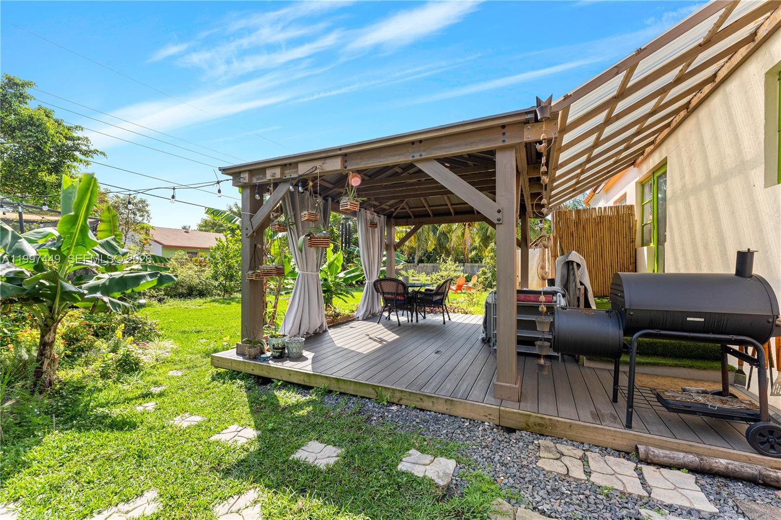 A wooden gazebo with a deck and a grill sits in a grassy backyard — 1601 N 16th Ct, Hollywood FL 33020, HOLLYWOOD, FL
