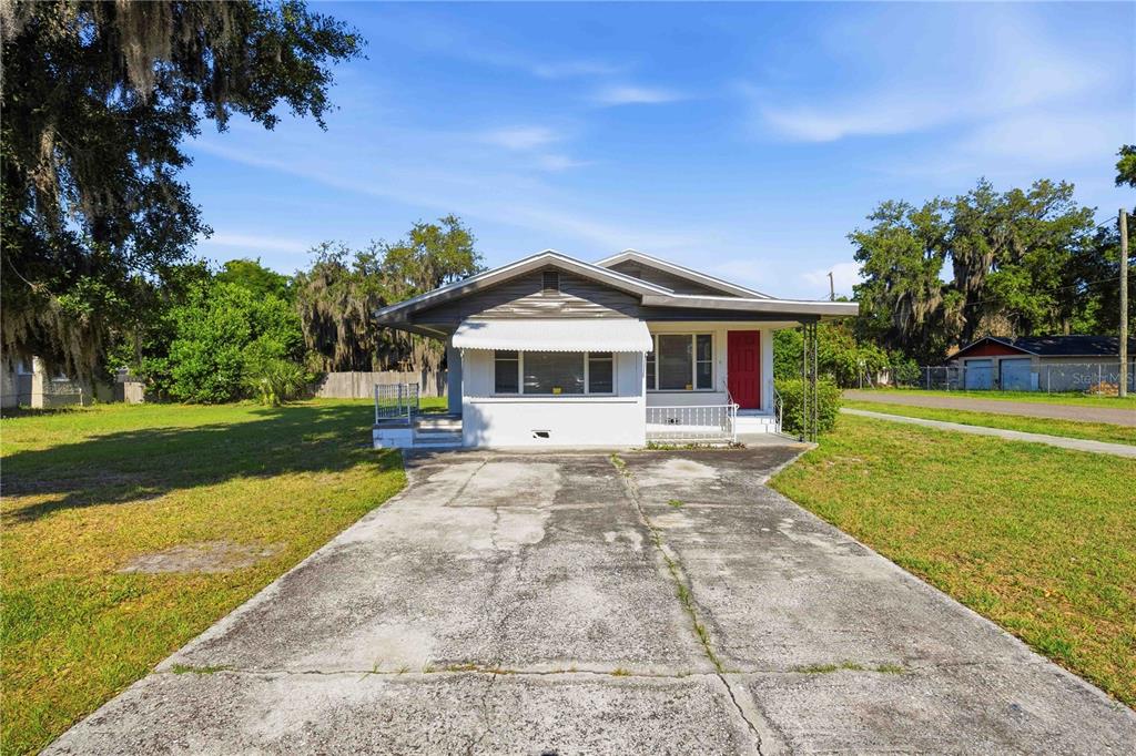 A single-story house with a concrete driveway, white exterior, and a red front door — 1997 26TH STREET NW, WINTER HAVEN, FL
