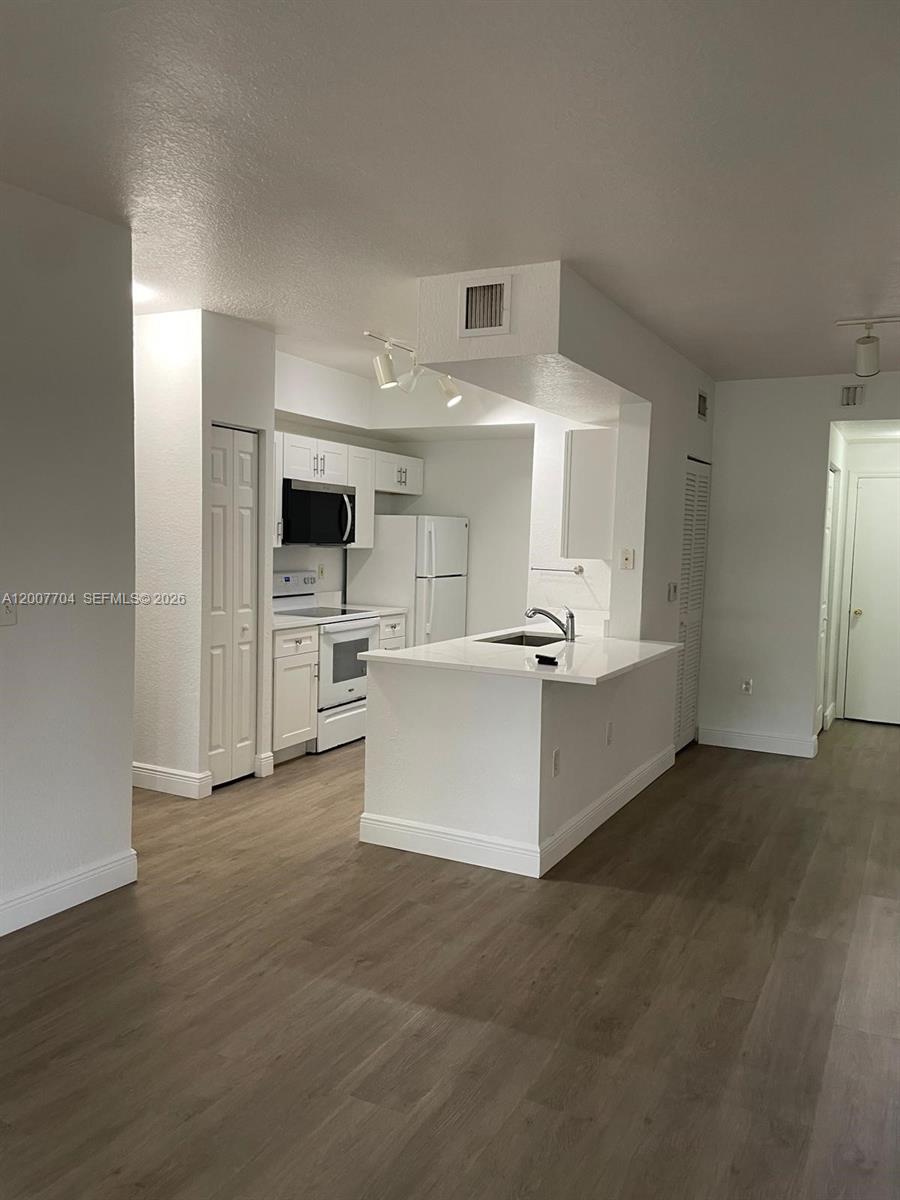 This kitchen features white cabinetry, stainless steel appliances, and a peninsula with a sink — 2500 Centergate Dr # 104, Miramar FL 33025, MIRAMAR, FL