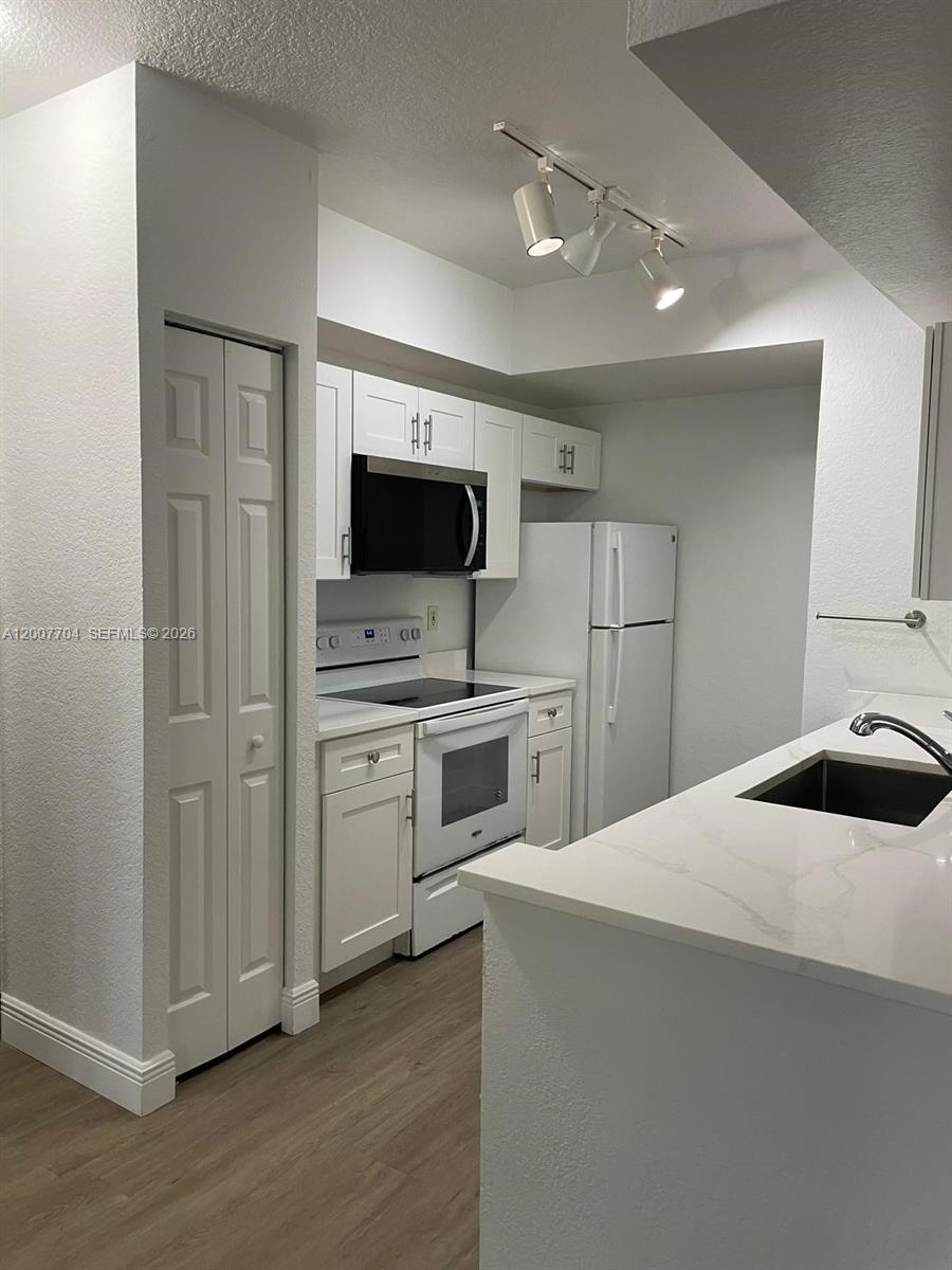 A kitchen features white cabinets, stainless steel appliances, and a white countertop with a sink — 2500 Centergate Dr # 104, Miramar FL 33025, MIRAMAR, FL