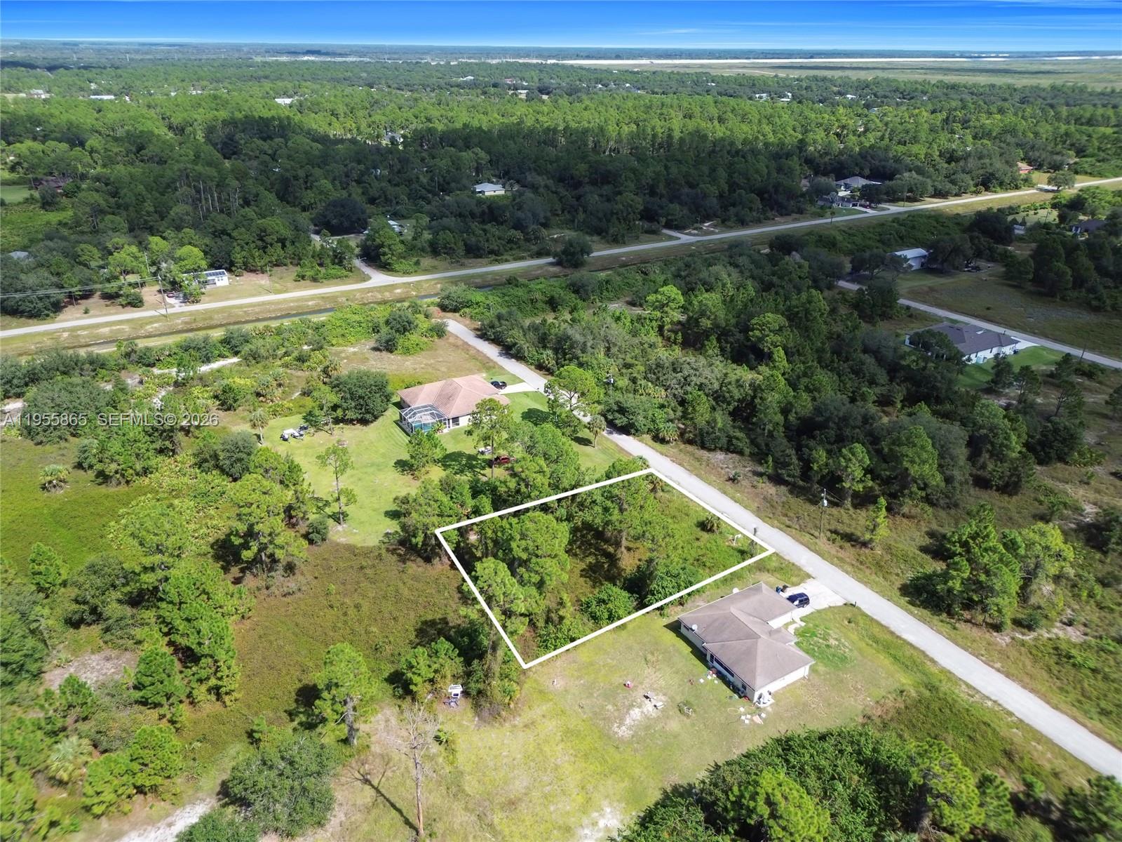 An aerial view shows a vacant, rectangular lot outlined in white between two residential houses — 1915 Louis Ave, Lehigh Acres FL 33972, LEHIGH ACRES, FL